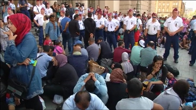 Refugiados sentados frente a la estación de ferrocarriles de Budapest