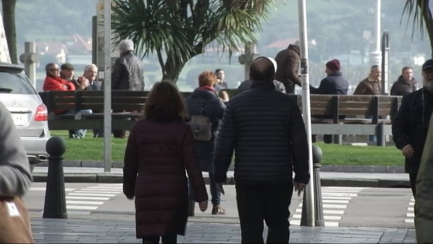 Demografía en Gijón, paseantes en una calle frente a la playa San Lorenzo