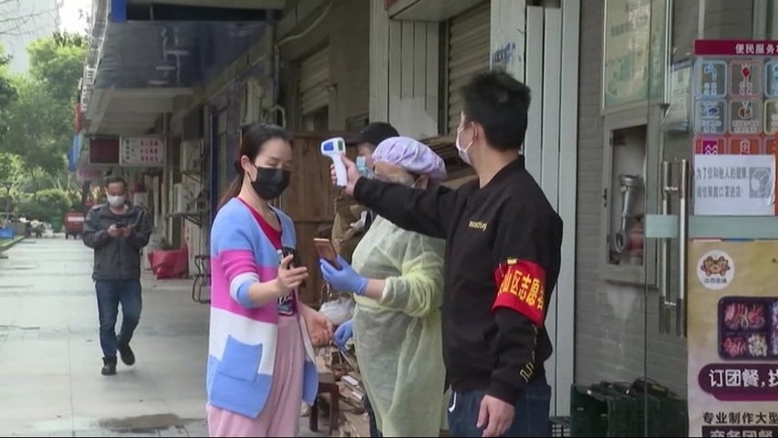 Ciudadanos de Hong Kong con mascarillas y midiéndose la temperatura corporal en las calles durante la cuarentena