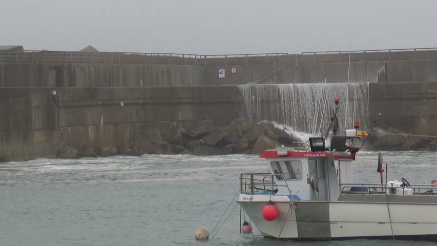 Una ola pasa por encima del espigón del puerto de Cudillero