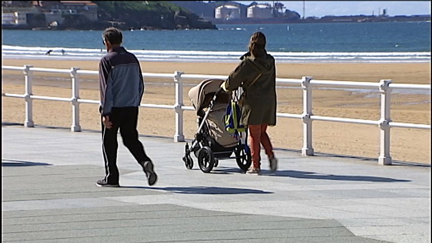 Una mujer pasea sola con su niño en carrito en el paseo del Muro