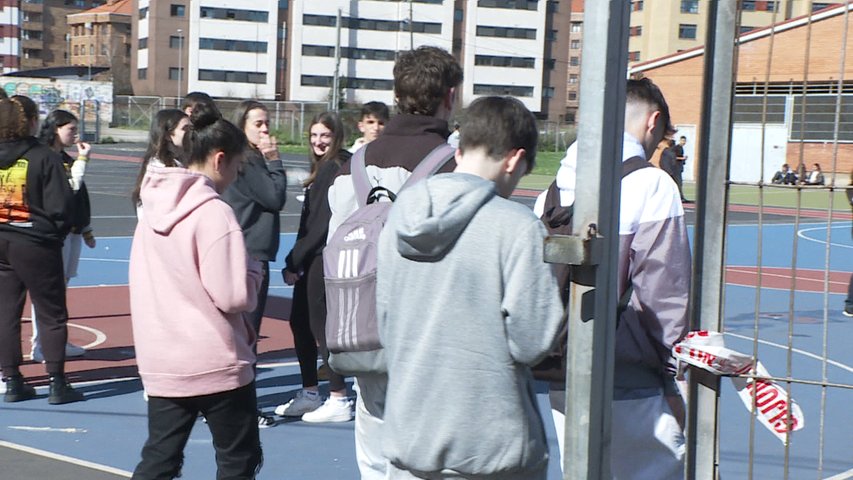 Jóvenes mirando sus móviles en el patio de un instituto